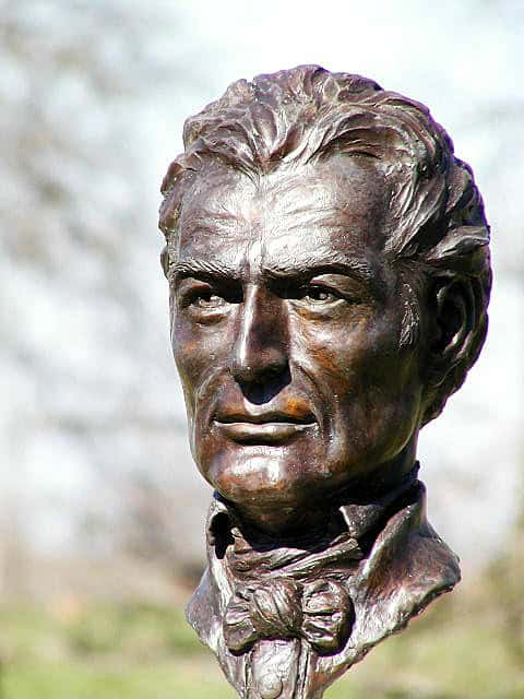 Close-up of a bronze bust of a man with a serious expression, wearing a bow tie, symbolizing Christian leadership and faith.