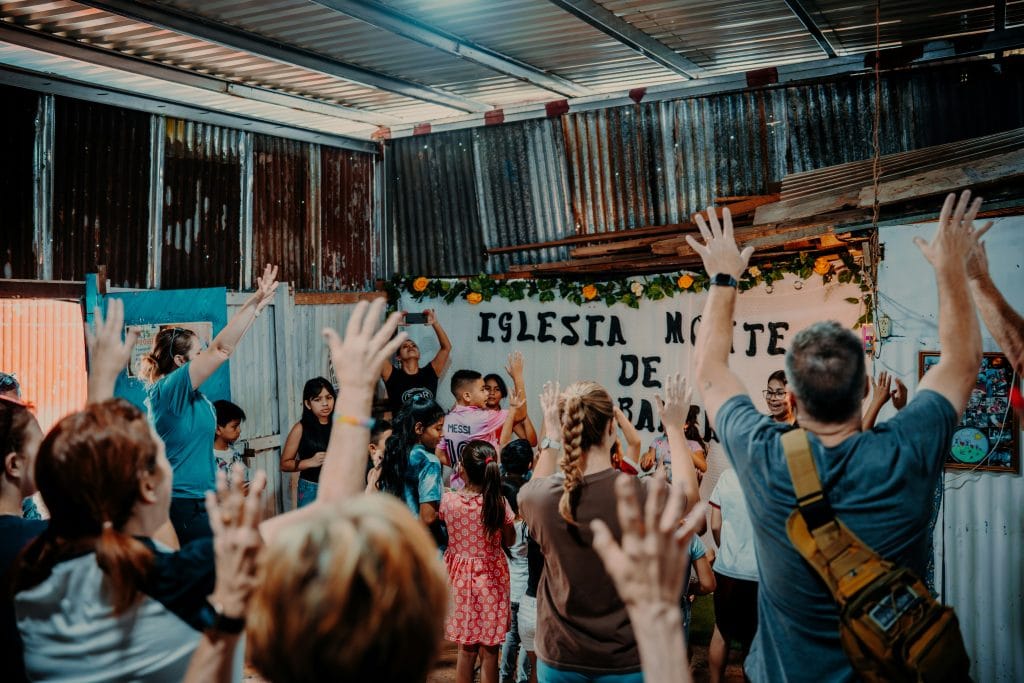 Churchservice with children and congregation raising hands in prayer and worship.