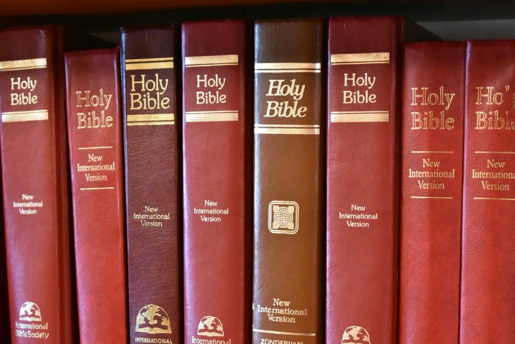 Alt: Close-up of red Holy Bible books on a church bookshelf for spiritual growth.