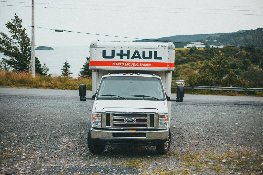 U-Haul moving truck parked in an open, scenic outdoor area with mountains and greenery in the background.