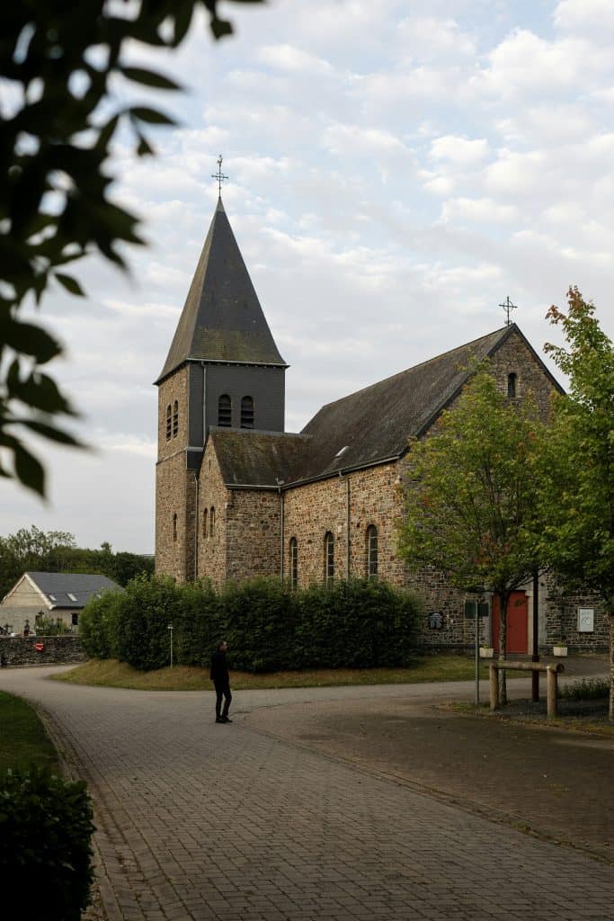 Old stone church with steeple and surrounding greenery.