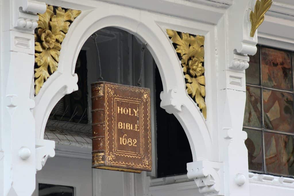 Historic Holy Bible on church wall, decorative white and gold church architecture, religious and faith symbol.