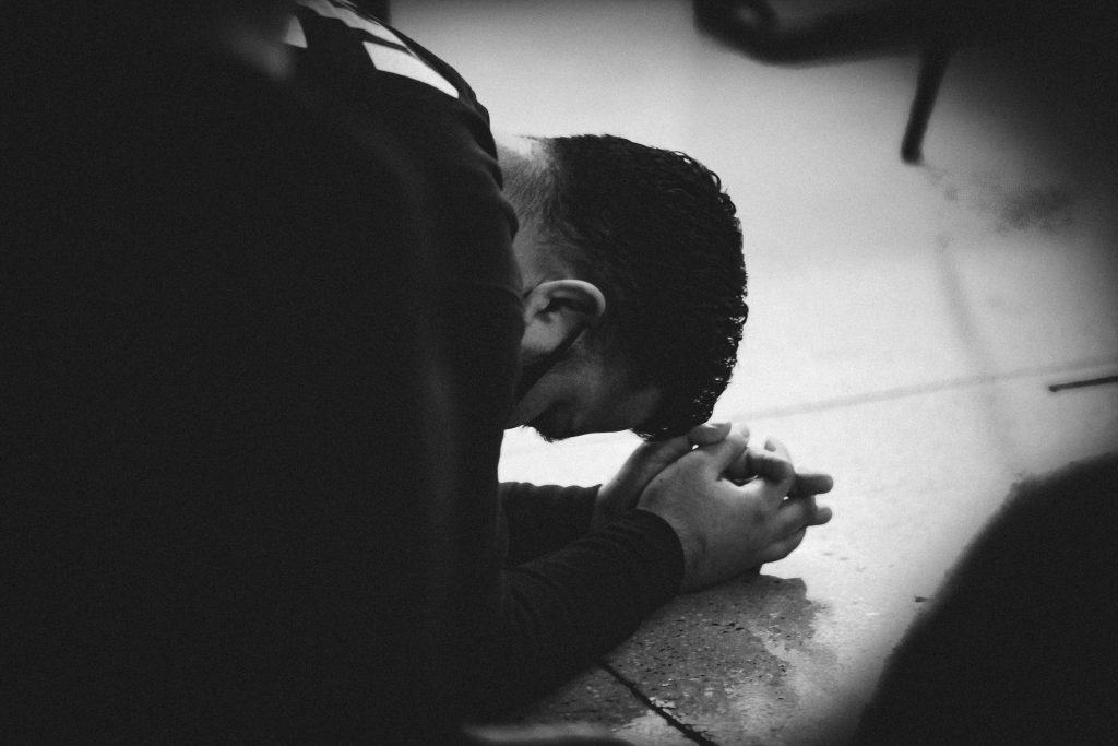 Praying student with bowed head in prayer at Church of Christ gathering.