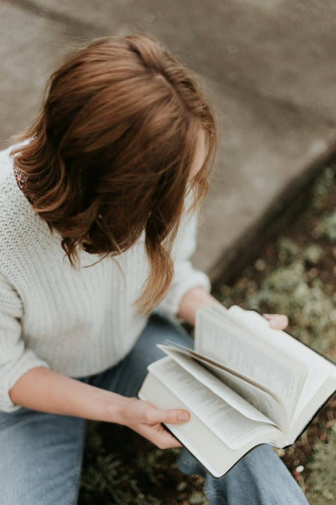 Woman reading Bible outdoors for spiritual growth and faith.
