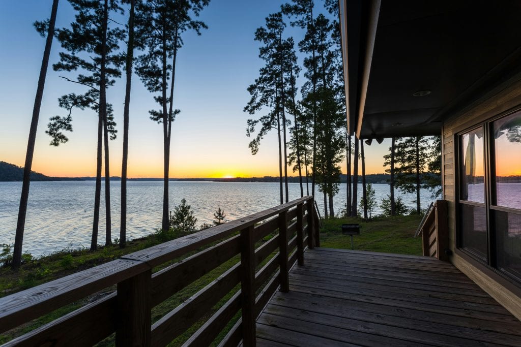 Lakeside sunset with calm waters and tall trees, perfect for relaxing and spiritual reflection.