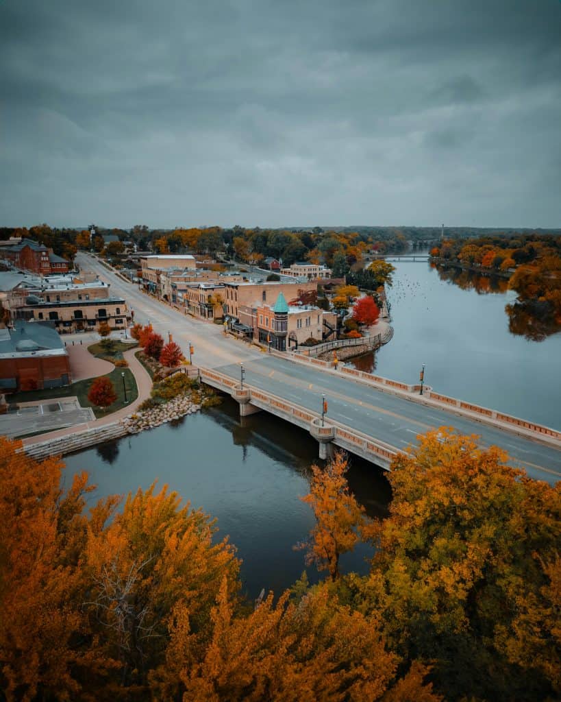 Historic river town with colorful fall foliage and a bridge over the water.