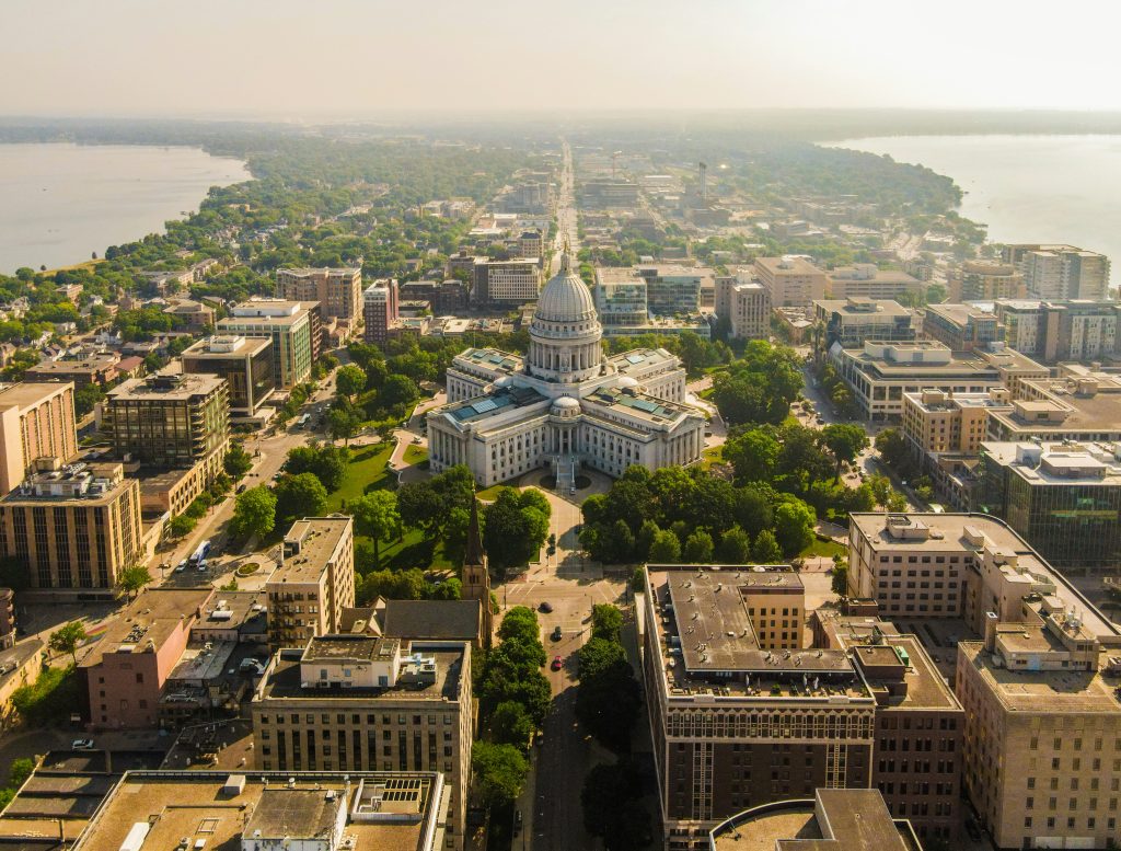 Capitol building in Madison, Wisconsin, aerial shot showing cityscape and surrounding water.