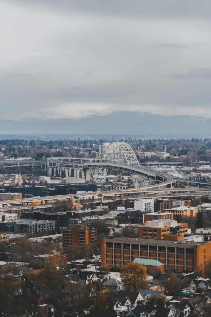 Portland cityscape featuring the iconic bridge and modern buildings under cloudy skies.